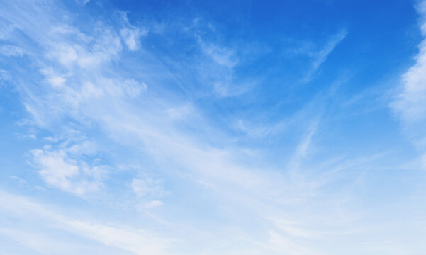 Soft clouds drift across a bright, clear sky