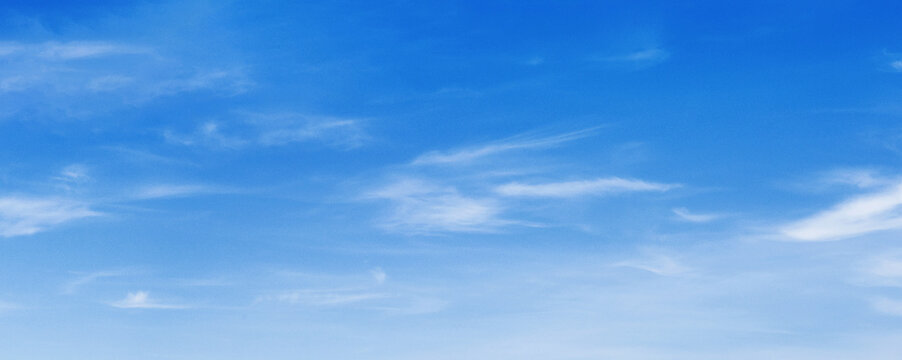 Clear blue sky with wispy clouds drifting above