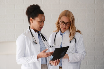 Fototapeta premium Female doctors sharing medical expertise and discussing a patient case while examining diagnostic imaging together