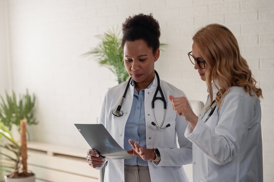 Two female doctors discussing medical imaging and sharing professional opinions during a clinical consultation