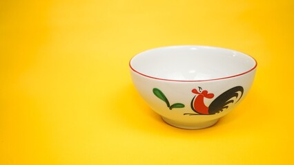 Traditional Asian rooster design ceramic noodle bowl isolated on bright yellow background © Liada
