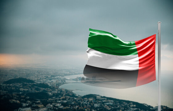 United Arab Emirates flag waving over a coastal city under dramatic cloudy sky, realistic fabric motion, aerial seaside landscape background. UAE national flag for independence day.