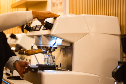 A barista prepares espresso on a modern coffee machine. Concept of a high-quality coffee beverage prepared with skill and precision in a professional setting. Ideal for coffee shop promotions.