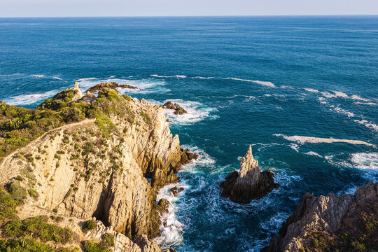 Aerial view of the Dedo de Dios rock formation rising from the Pacific Ocean near the rugged cliffs of Maruata, Michoacan, Mexico.