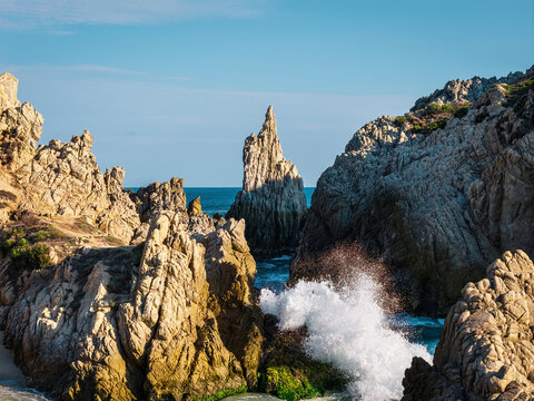 Aerial view of Dedo de Dios rock formation surrounded by rugged cliffs and crashing waves along the Pacific coast in Maruata, Michoacan, Mexico.