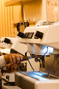 Barista preparing espresso using a professional coffee machine at a modern cafe, focusing on skill and the art of brewing.Aromatic flavor of freshly made coffee concept. Vertical real picture