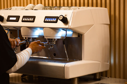 Barista preparing fresh aromatic espresso using a professional coffee machine at a modern cafe, focusing on skill, quality, and the art of brewing