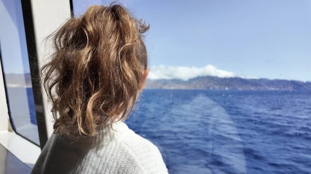 Young girl looking through window on a boat