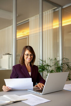 American businesswoman reading document, reviewing paperwork at office desk, vertical. Middle-aged business woman works as advisor consultant banker, checking job resume, audit ready. Career concept.