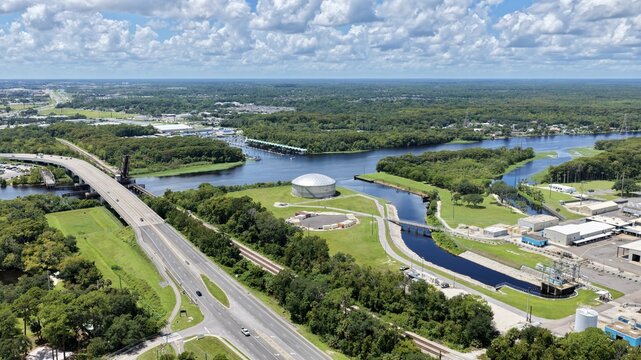 Aerial view of the FPL Sanford Power Plant along the St. Johns River, featuring a large storage tank, highway bridge, and green surroundings in DeBary, Florida, United States.