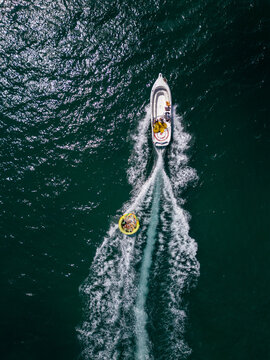 Aerial View of Speedboat Towing Inflatable Tube on Deep Blue Sea