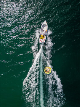 Aerial View of Speedboat Towing Inflatable Tube on Deep Blue Sea
