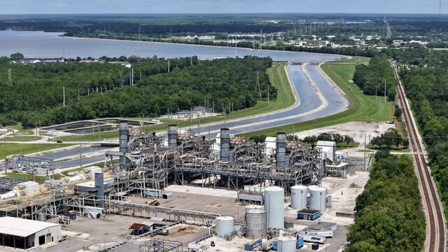 Aerial view of the FPL Sanford Power Plant industrial facility featuring cooling water canals, storage tanks, and adjacent railroad tracks in DeBary, Florida, United States.
