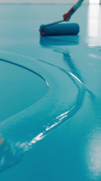 Worker applying blue epoxy resin floor coating