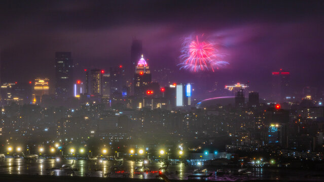 Fireworks over Taipei skyline beyond an airport on a rainy night