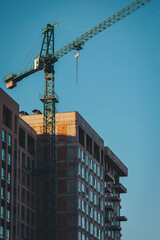 Fototapeta premium Urban construction reaches new heights with a towering crane against a clear blue sky
