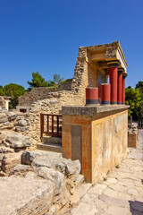 Naklejka premium A reconstructed section of the Palace of Knossos on Crete, Greece, featuring the characteristic red Minoan columns, decorated architectural elements and a colorful bull fresco.