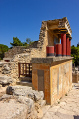 Naklejka premium A reconstructed section of the Palace of Knossos on Crete, Greece, featuring the characteristic red Minoan columns, decorated architectural elements and a colorful bull fresco.