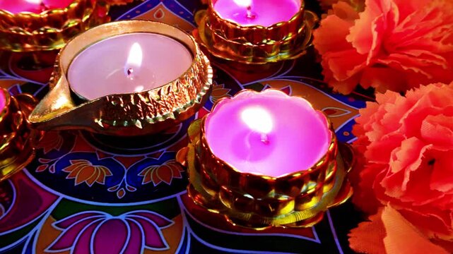 Burning Diwali candles on a colorful Rangoli background