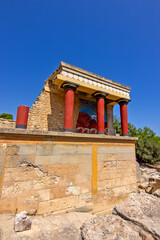 Naklejka premium A reconstructed section of the Palace of Knossos on Crete, Greece, featuring the characteristic red Minoan columns, decorated architectural elements and a colorful bull fresco.