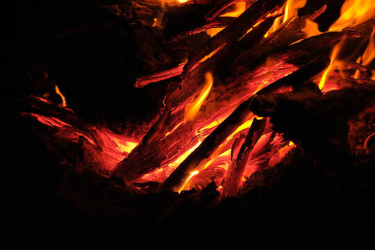 Close-up of red-hot burning wood and glowing embers in a dying campfire.