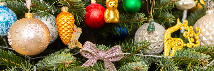 Naklejka premium A Christmas tree stands with many colorful ornaments hanging from its branches. Each ornament shows different shapes and colors, celebrating the festive season and bringing joy to the home