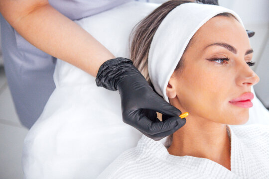 Female patient receiving skincare treatment in a modern clinic, with a professional applying a product to her face, showcasing beauty and wellness in a serene environment