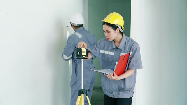 Two construction engineers inspecting building interior with laser level