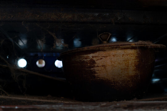 Forgotten pot rests beneath the dusty stove, a glimpse into a world of old memories and silent stories untold