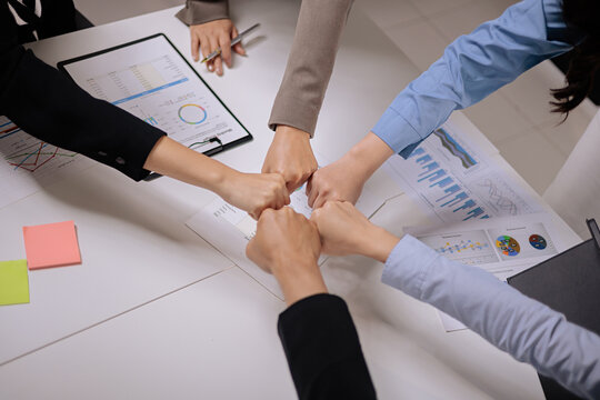 Business Team Fist Bump Over Meeting Table with Charts and Reports