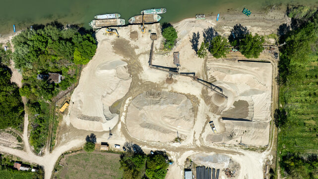Aerial Drone View of Riverside Sand and Gravel Quarry with Barges, Excavators, and Conveyor Belt, Industrial Mining Site from Above