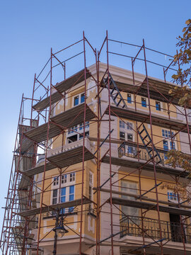 Facade restoration of a historic building with extensive metal scaffolding. Concept of urban renewal, construction, and real estate development.