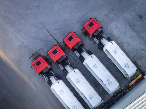 Aerial view of four red cement tanker trucks parked in a row on a concrete surface in Krakow, Lesser Poland Voivode, Poland.