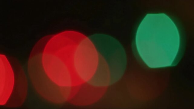 Vibrant glowing orbs of emerald green and ruby red create a festive atmosphere that captures the joyous spirit of holiday celebrations through a shimmering display of out of focus light patterns