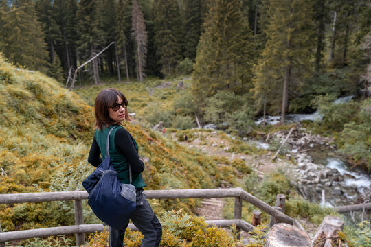 Woman standing on a path, enjoying a view of a mountain river and forest