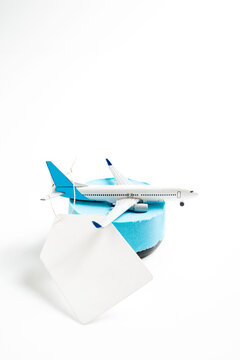 A model airplane on a blue foam block with a blank white tag, isolated on a white background. Ideal for travel, sales, and booking concepts. Mockup or Copyspace