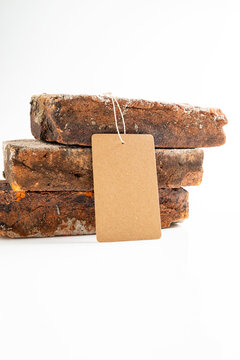 Three stacked reclaimed rustic bricks on a white background with a blank kraft paper price tag hanging from them. Mockup or Copyspace