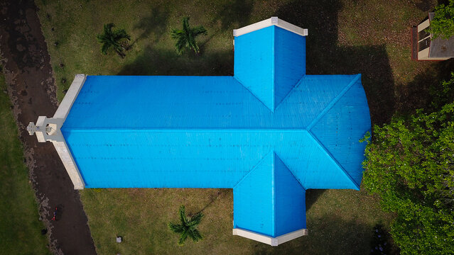 Aerial view of Chamarel Church with its distinctive bright blue roof set amidst lush green grounds and palm trees in Chamarel, Riviere Noire District, Mauritius.