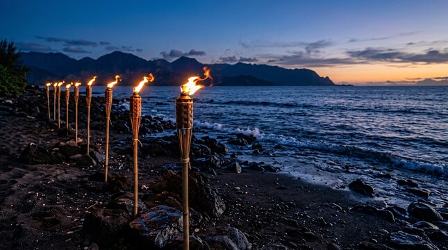 Burning bamboo tiki torches lined on dark rocky beach, vibrant orange flames against cool blue twilight ocean and distant mountains.