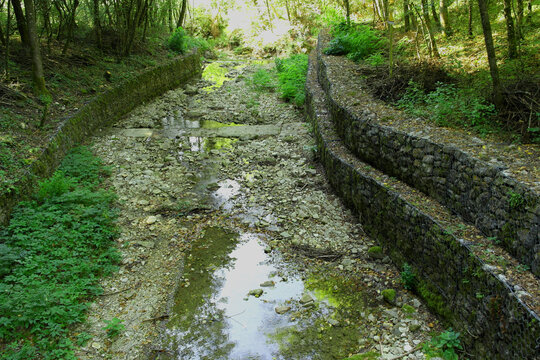 Retaining stone walls and gabions reinforcing a dry stream bed in Brent de l'Art, Italy