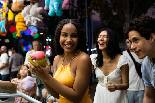 Diverse friends enjoying carnival game at amusement park night