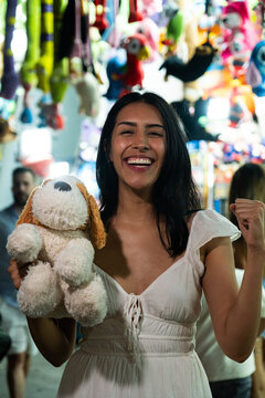 Smiling woman holding a prize, celebrating success at an amusement park