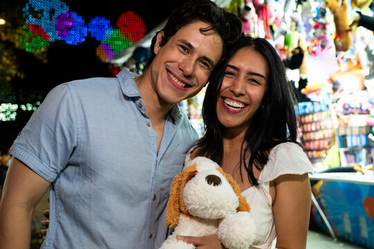 Smiling young couple having fun at a fairground with their new prize