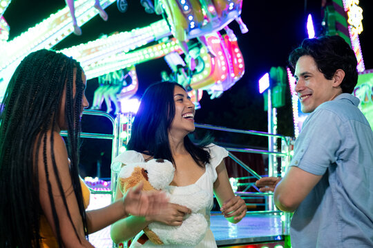 Group of friends laughing and holding a plush toy at a carnival
