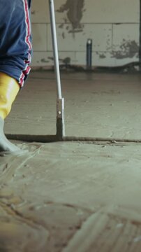 Construction worker leveling wet concrete screed