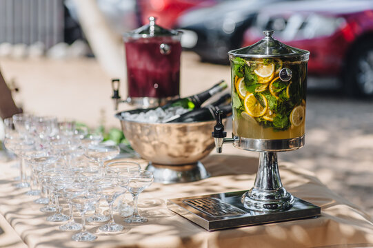 Close-up photo of fresh lemonade with ice, mint and lemon in dispenser on banquet table.