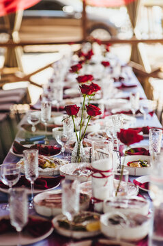 Photo of a banquet, buffet table setting in a restaurant, red flowers, roses, dishes and food.