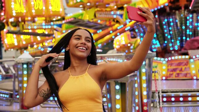 Joyful young woman taking a selfie with her smartphone at an amusement park