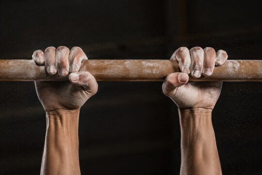 Chalked hands gripping a gymnastics bar