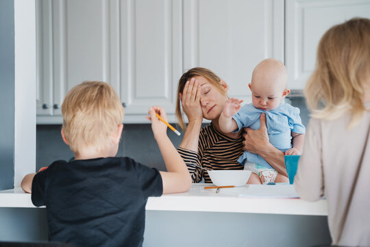 Young exhausted woman with three children at home.